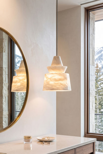 Tobiah Tiered Alabaster Pendant Light | Natural Alabaster and Metal | Installed in a bathroom vanity area near a round mirror and marble counter | vexa lamps