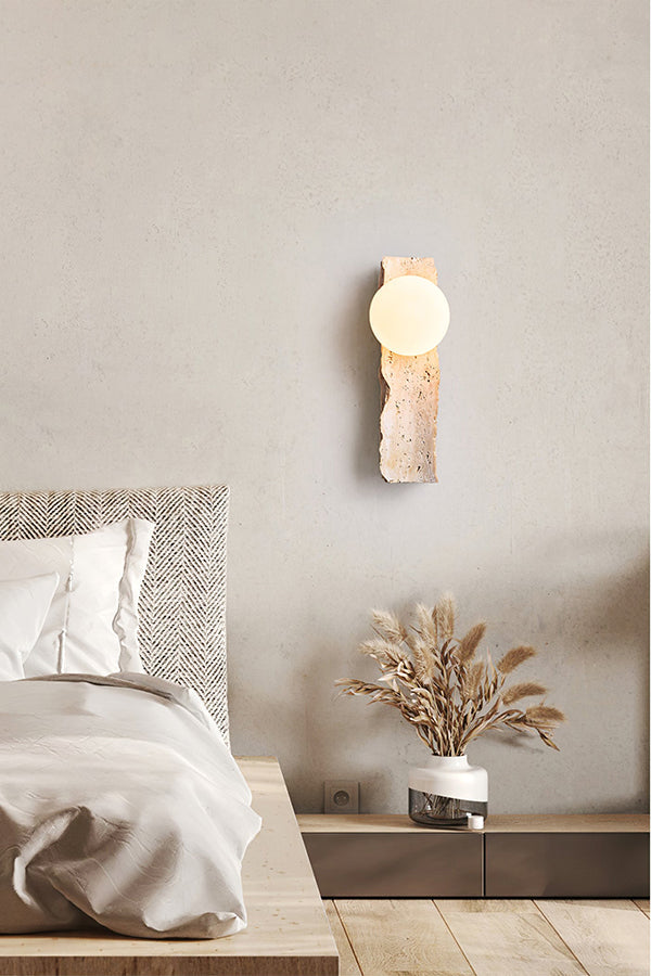 Travertine block wall sconce in a serene bedroom | Yellow Travertine, Metal, Glass | Mounted on a textured wall above the bed | vexa lamps