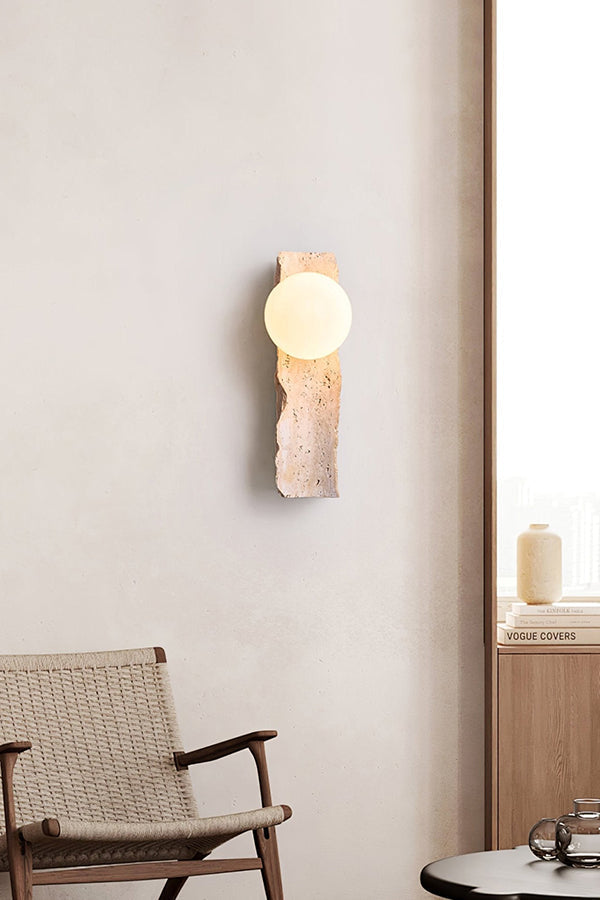 Minimalist stone wall lamp in bright interior | Yellow Travertine, Metal, Glass | Mounted on a clean wall near a wooden chair | vexa lamps