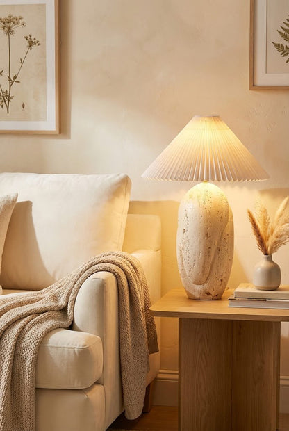 Lit travertine table lamp providing warm light | Travertine, Fabric | On a side table next to a cream sofa | vexa lamps