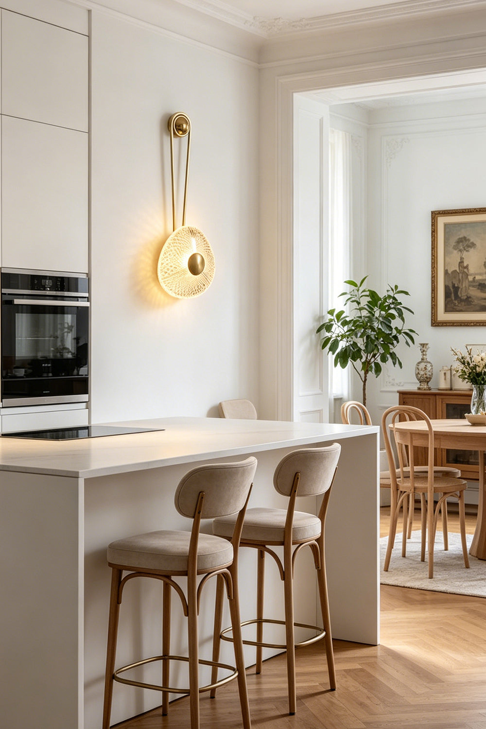 Vara Aura Woven Acrylic Wall Lamp | Woven Acrylic, Brass | Styled on a kitchen wall next to a modern white kitchen island with matching upholstered bar stools | vexa lamps