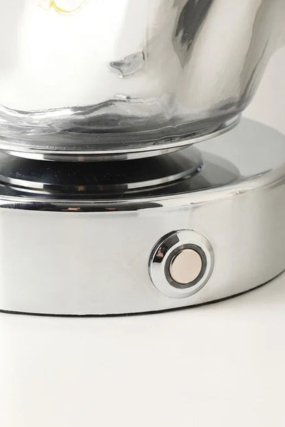 Close-up of the base and switch of the Vega Molten Metal Table Lamp showcasing its reflective surface.