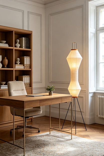 Verena Hourglass Paper Floor Lamp illuminating a modern office with a wooden desk and shelves.