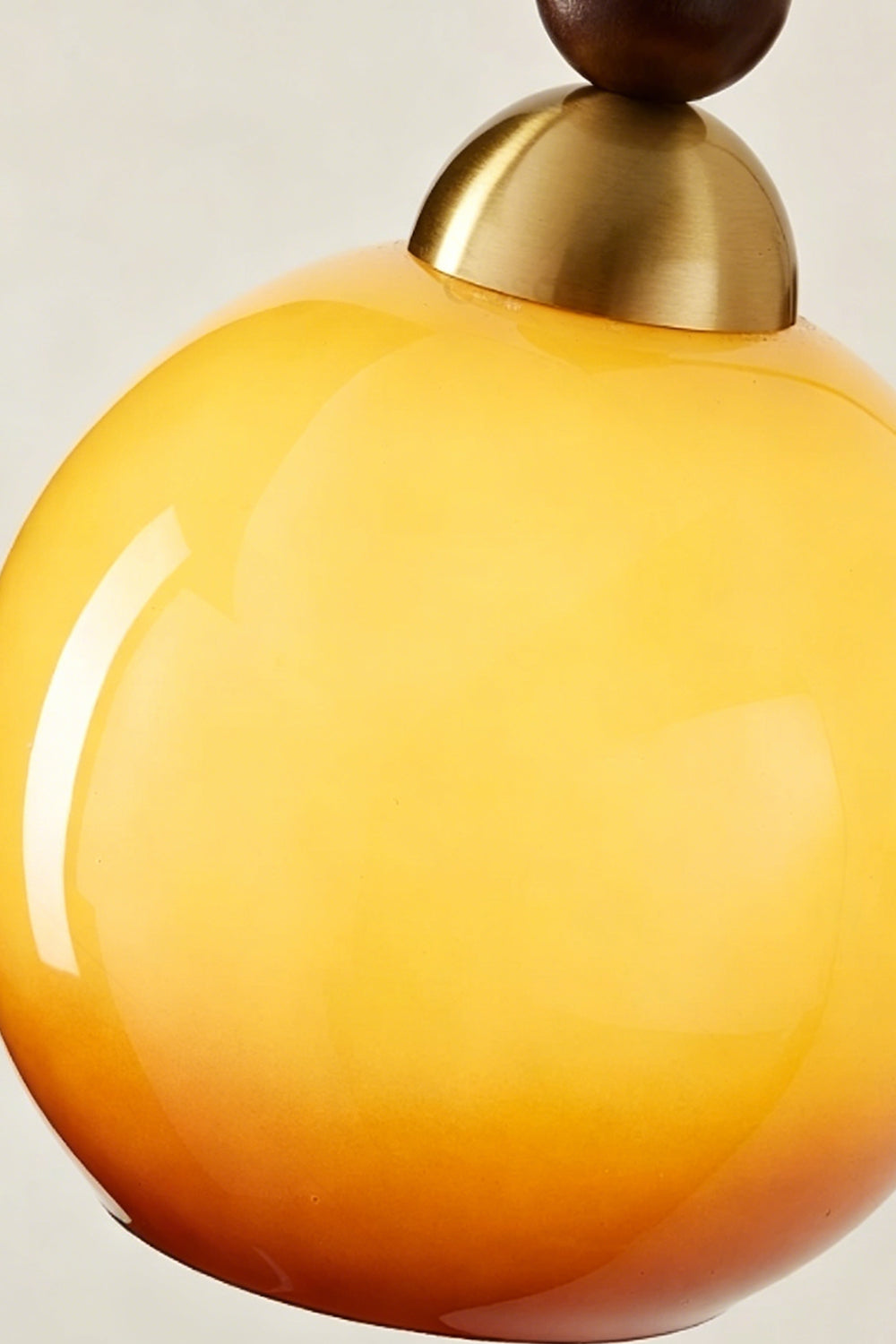 Vesper Caramel Gradient Wall Lamp | Glass, Metal, Wood | Macro shot highlighting the smooth glossy surface and warm orange-to-yellow color gradient of the glass shade | Detail shot | vexa lamps